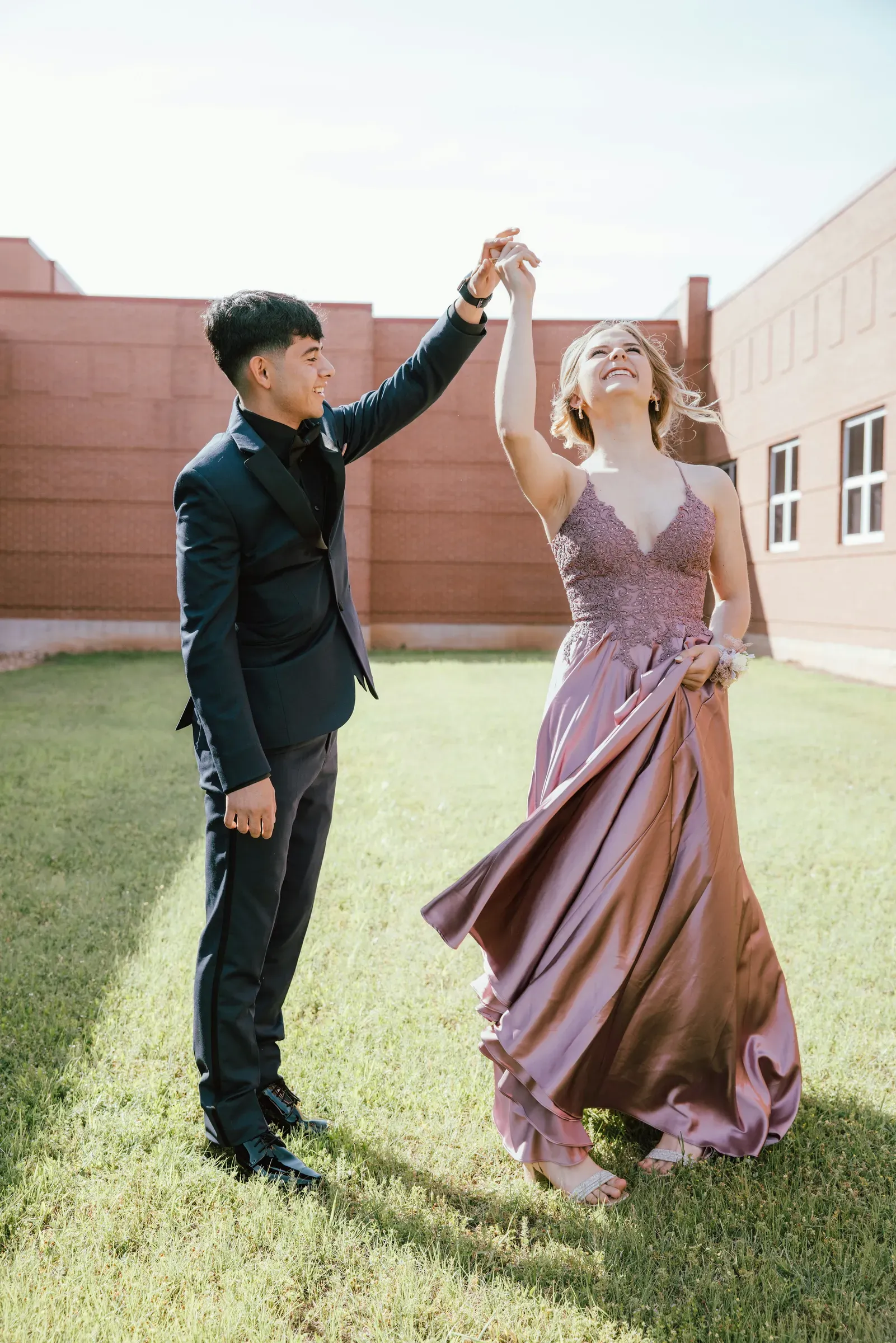He twirls her on the school lawn, the mauve satin dress catching the light.