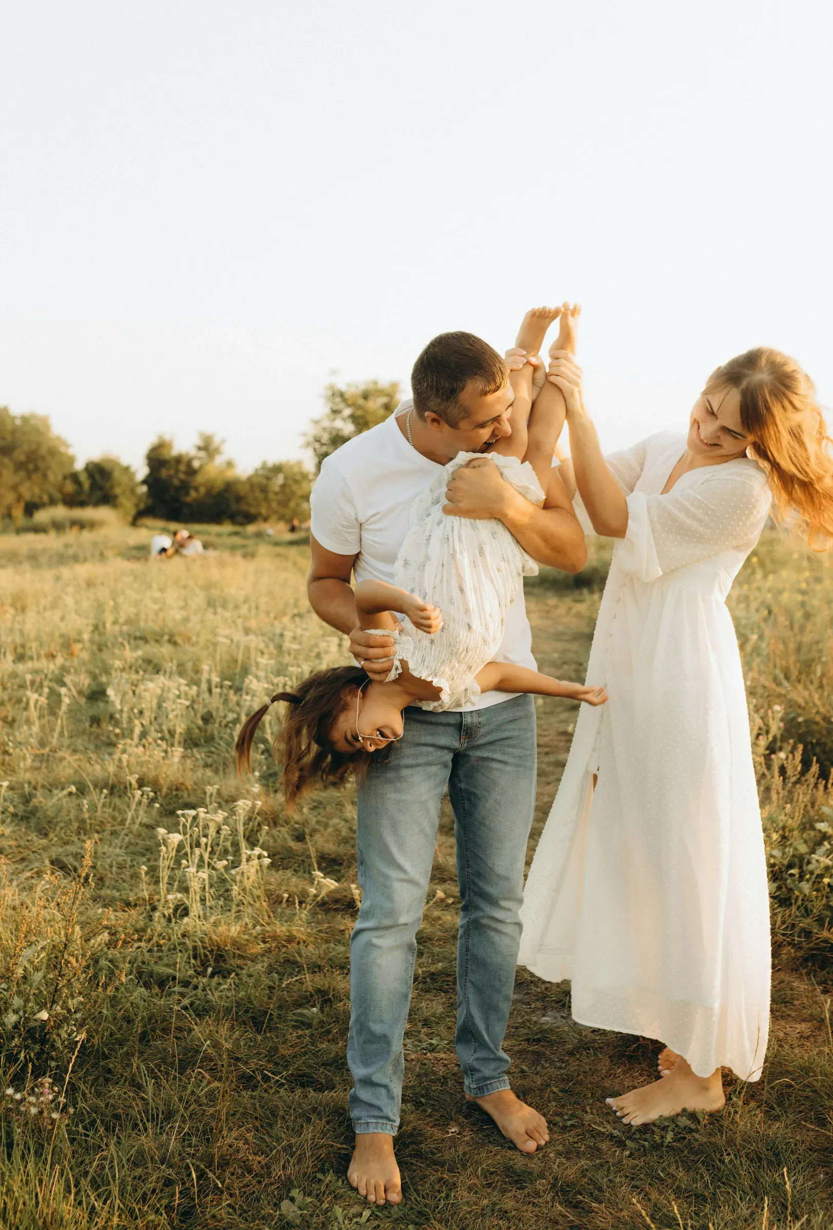 Their daughter hangs upside down between Mom and Dad, laughing the whole way over.