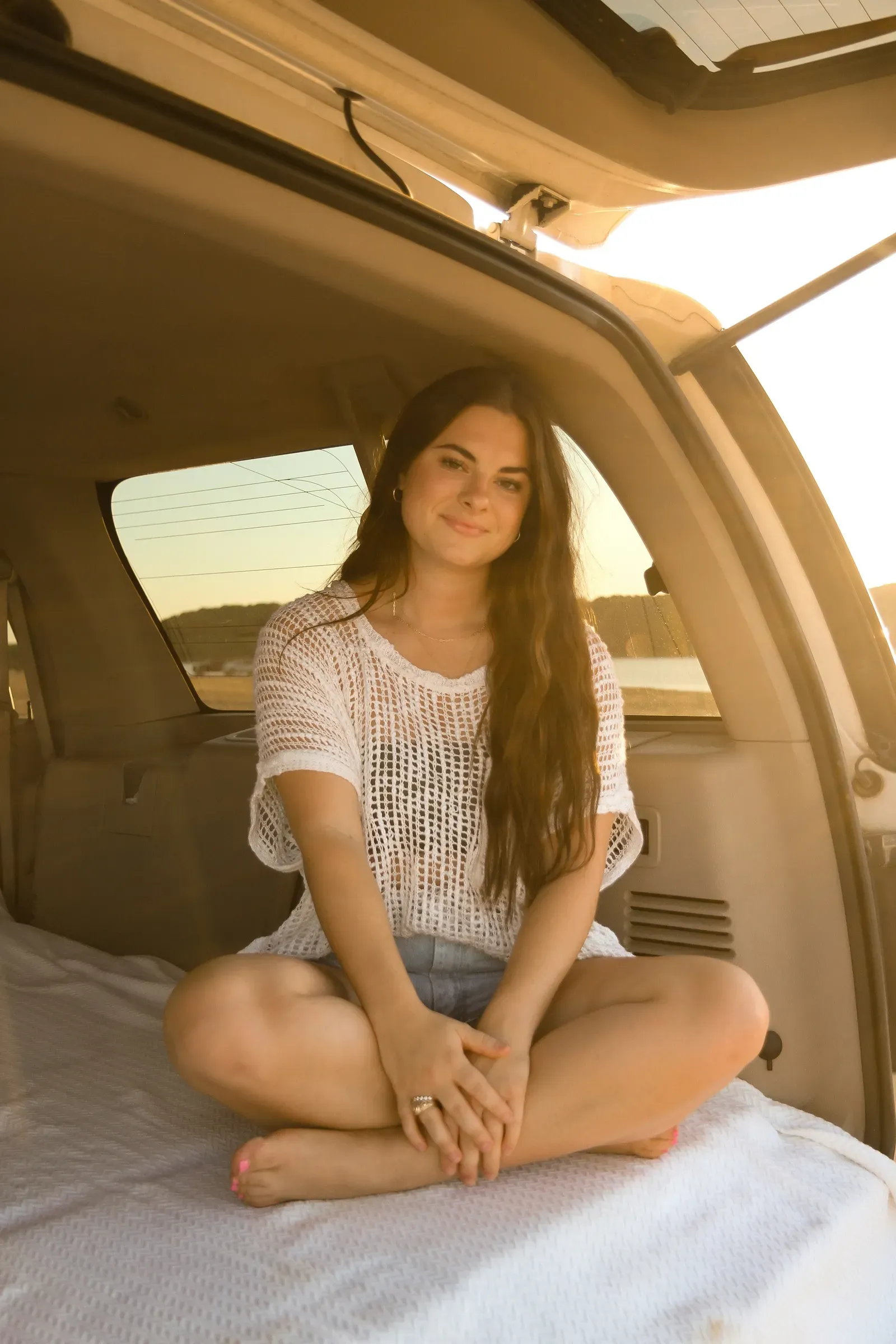 Sitting cross-legged on the tailgate blankets in her white crochet top.