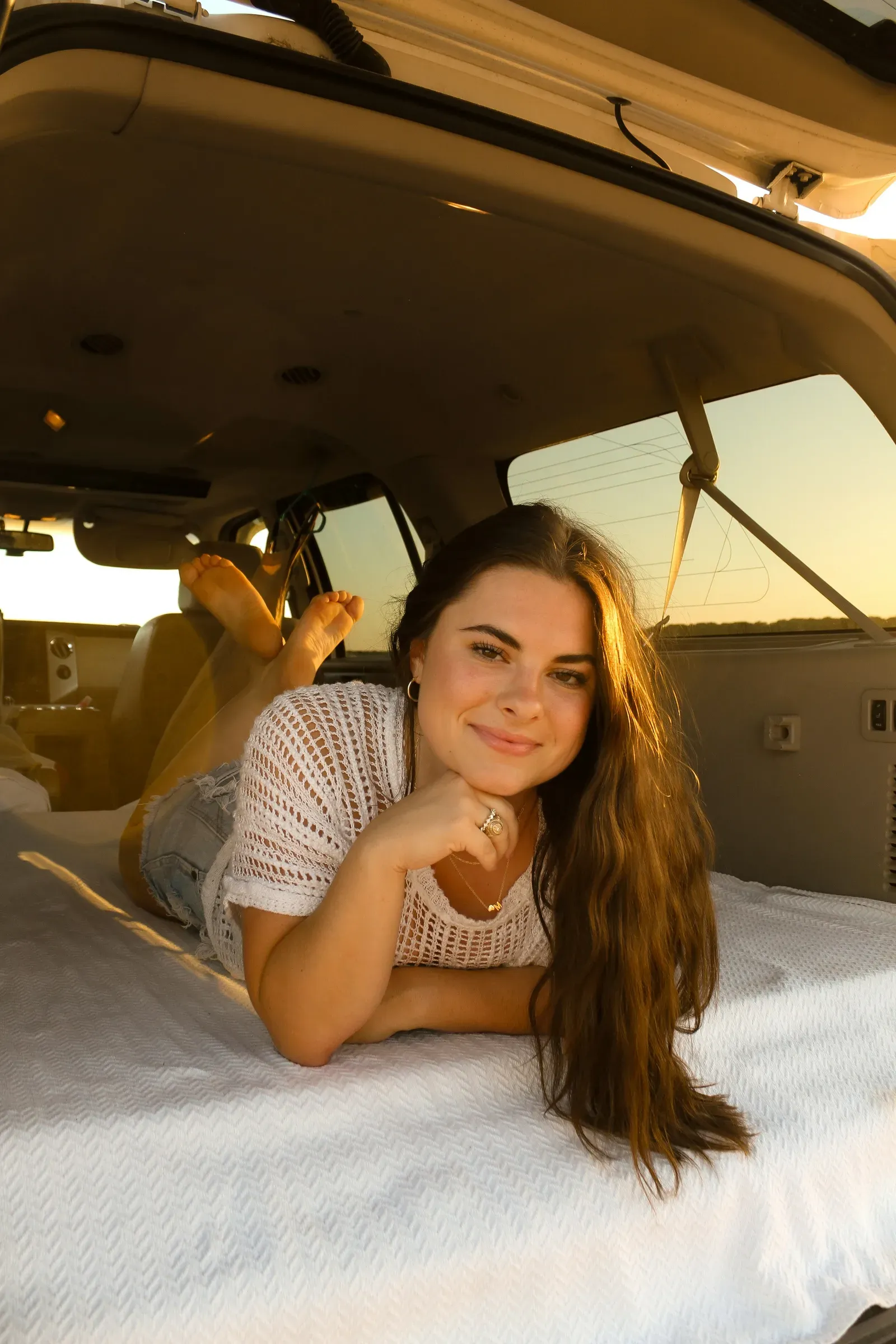 Stretched out on the quilt in the back, chin on her hand, golden light pouring in.