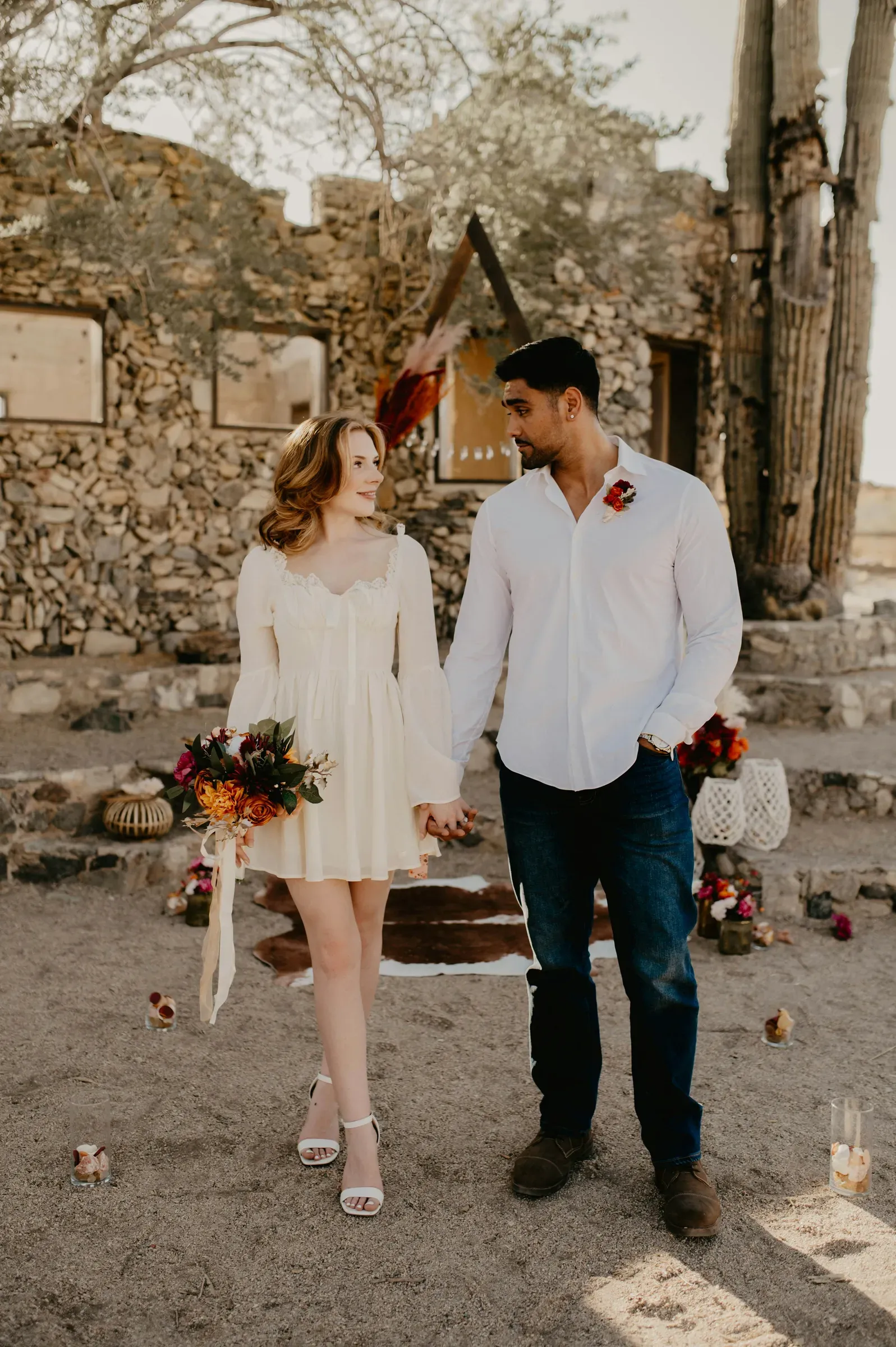The newlyweds walk out hand in hand past the stone walls in the low afternoon sun.