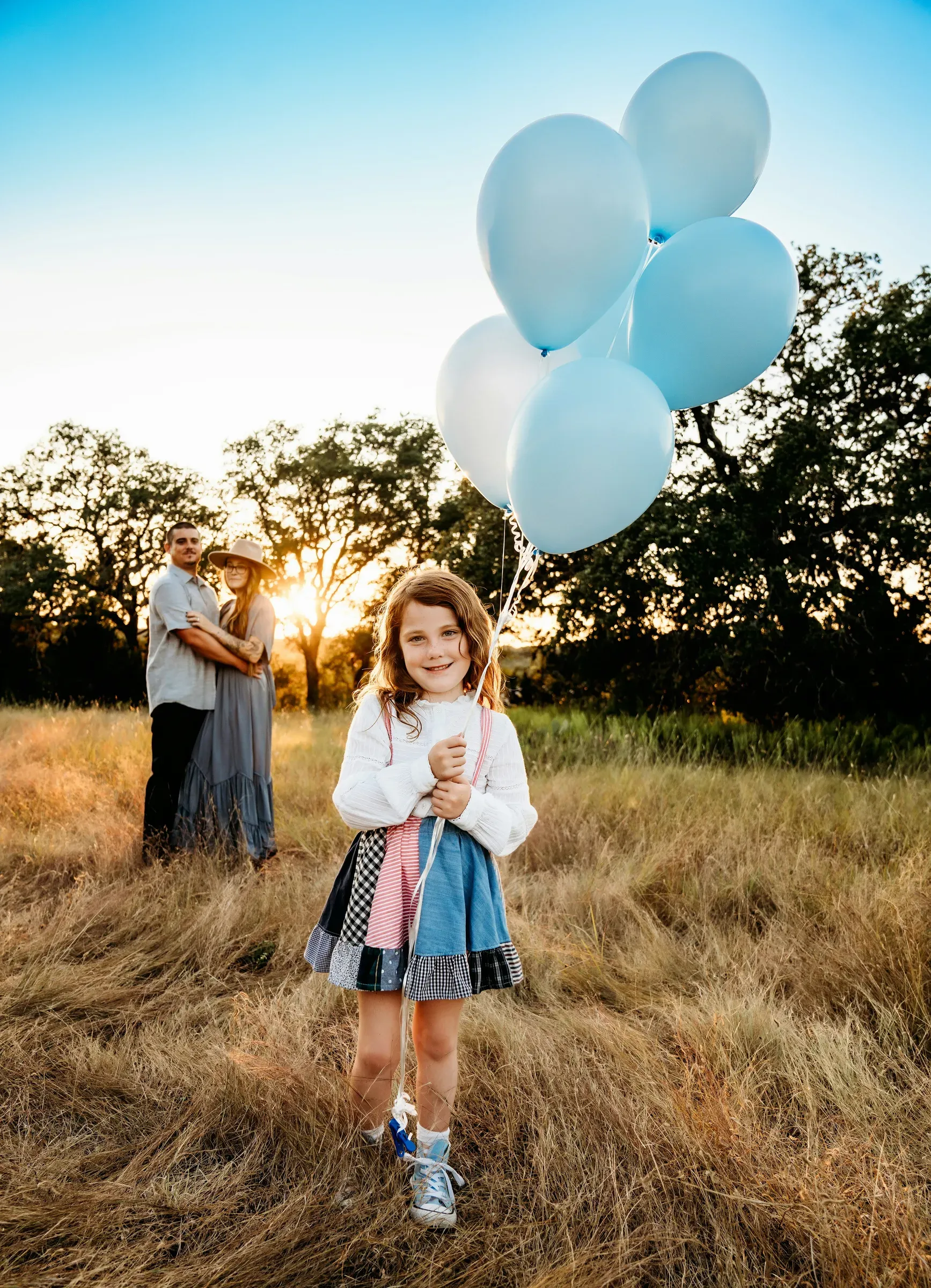 She hugs the string of blue balloons like she already owns the news.